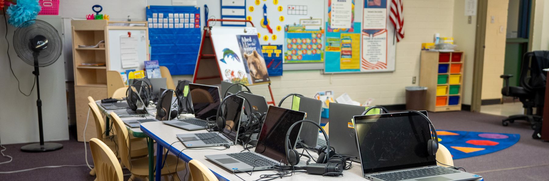 several laptops lined up next to each other on table in classroom