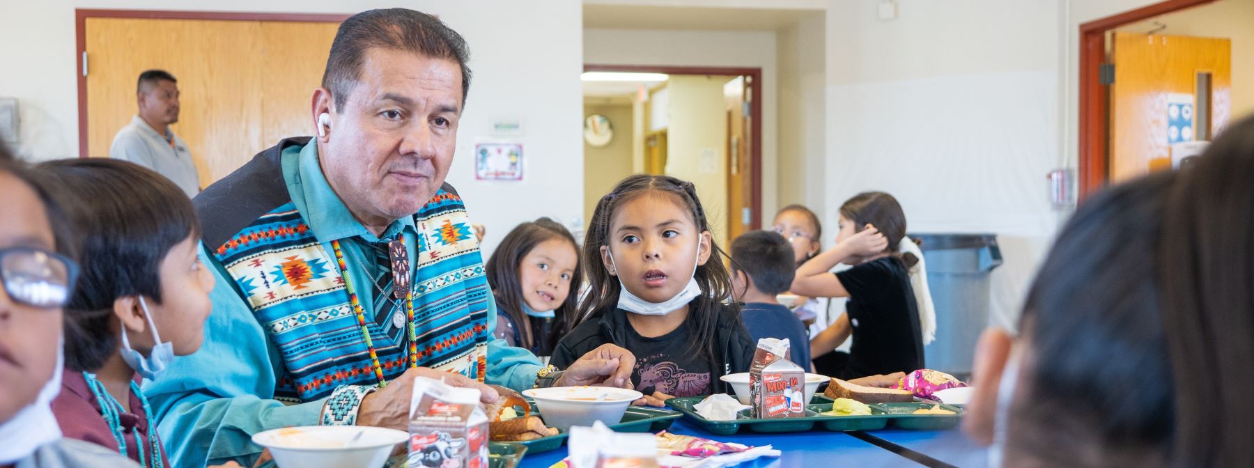 Students sitting at table having lunch together.